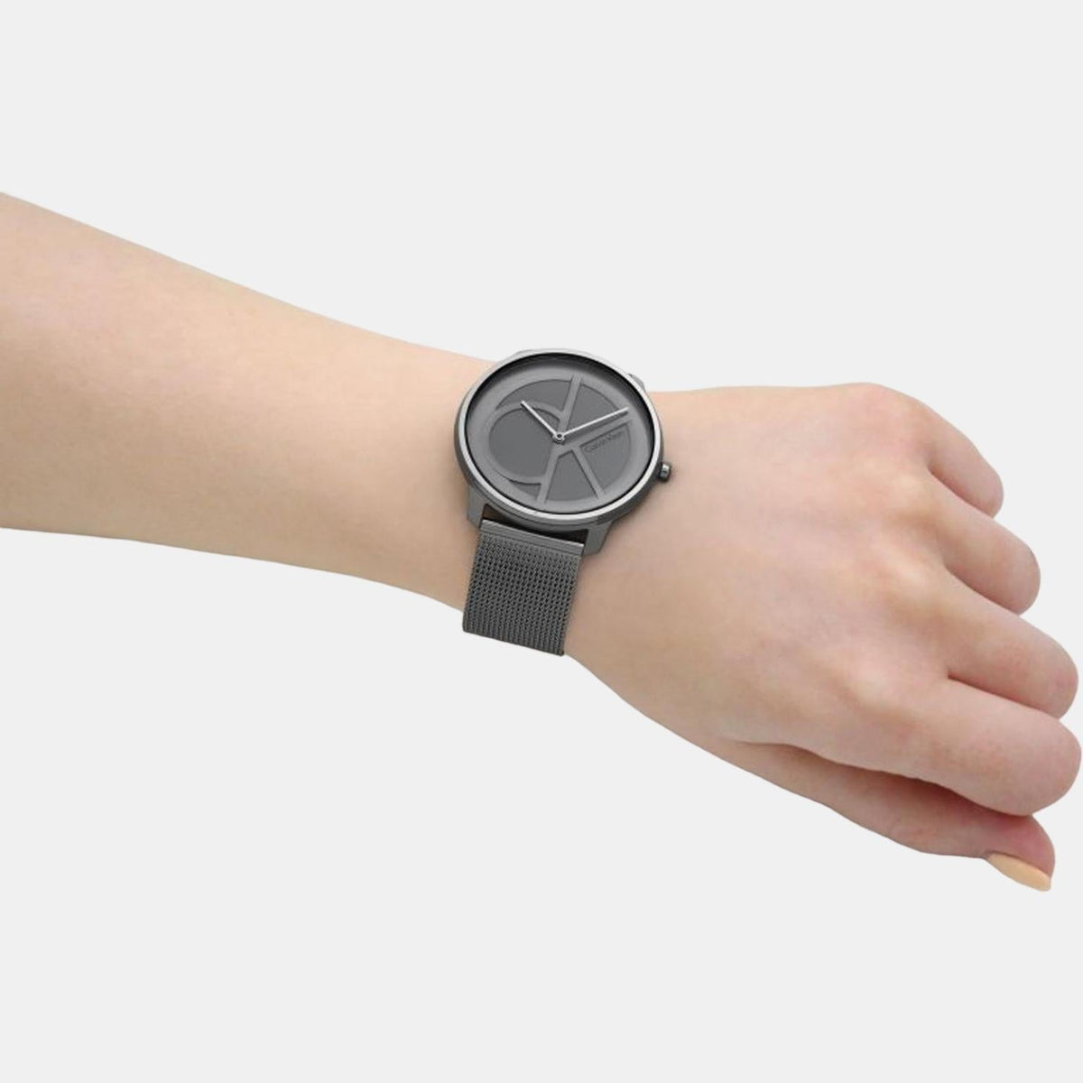 Calvin Klein watch on wrist showing grey sunburst dial and gunmetal mesh