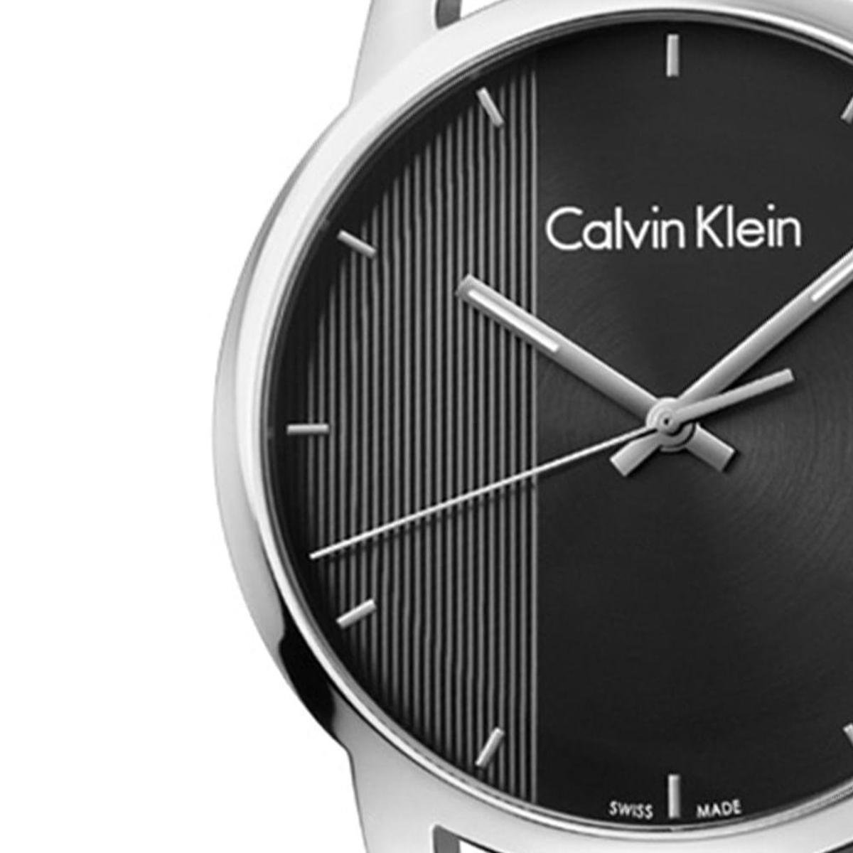 Close-up of black dial with vertical stripe pattern, Calvin Klein branding and silver hands