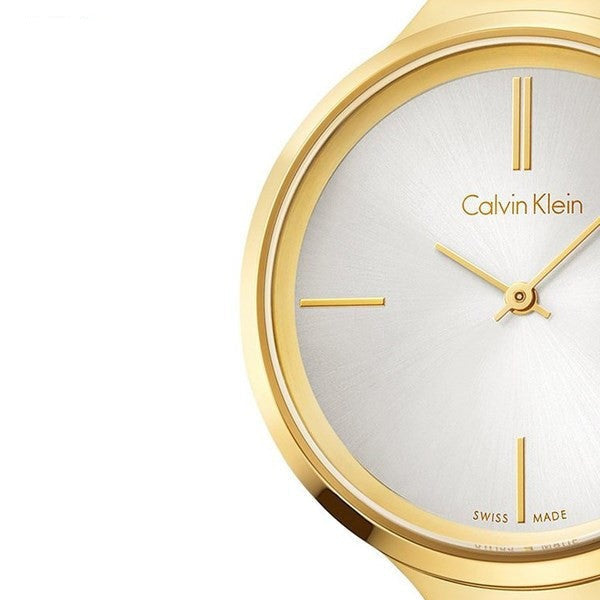Dial detail of Calvin Klein Lively watch showing silver face with gold markers and Calvin Klein branding
