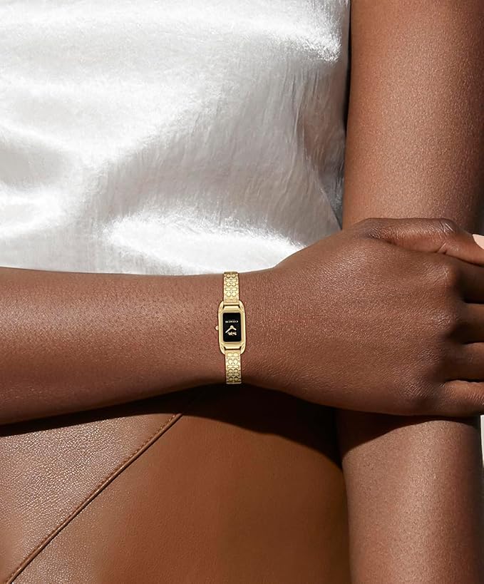Coach Cadie gold-tone bangle watch worn on wrist with black dial visible