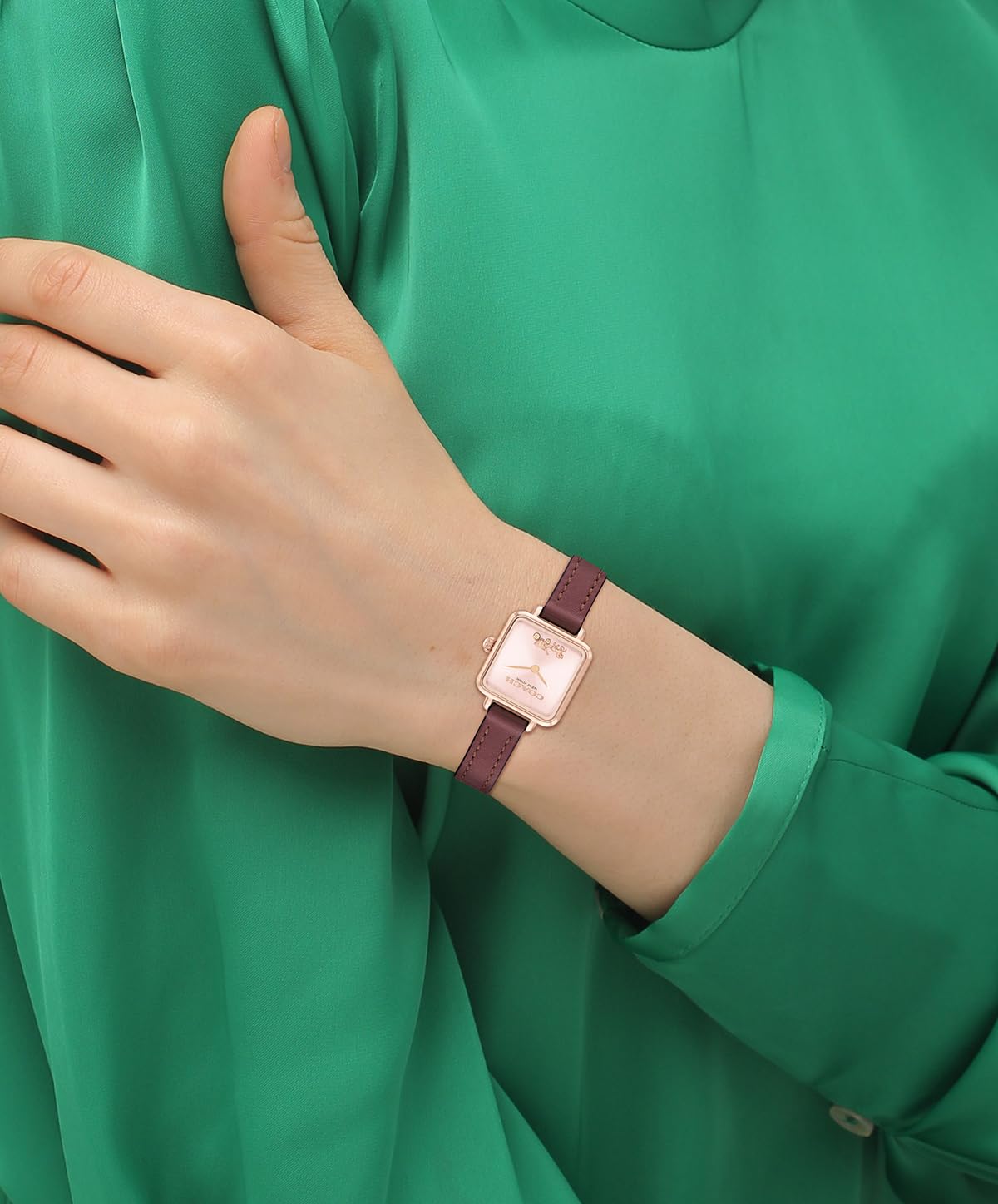 Coach Cass watch on wrist with blush dial and burgundy leather strap