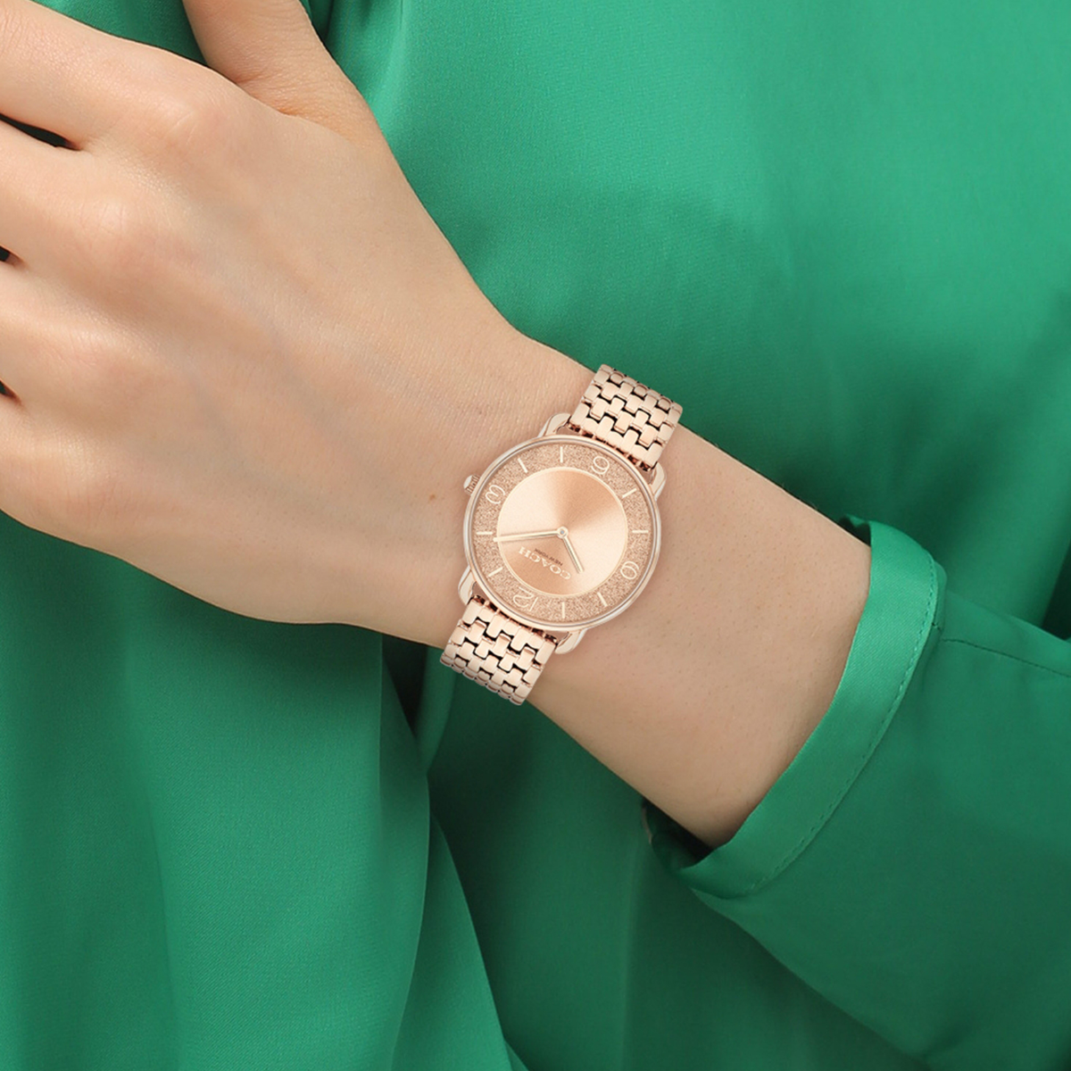 COACH Elliot rose gold watch worn on wrist with rose gold bracelet