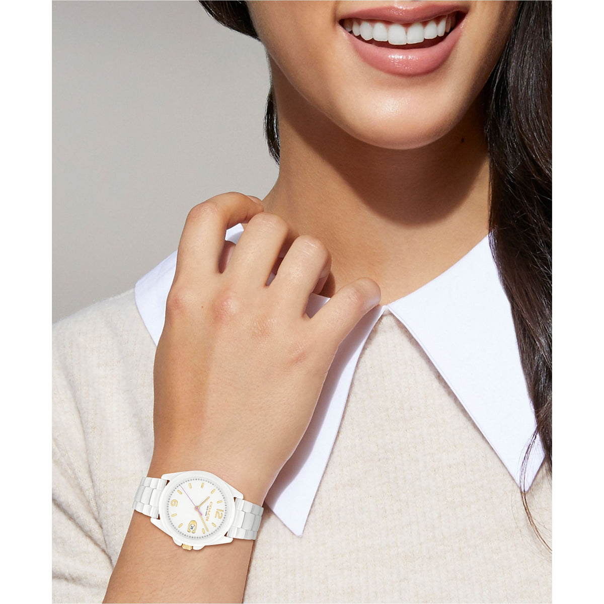 Coach Greyson white ceramic watch worn on wrist, showing dial with gold accents and lavender hand