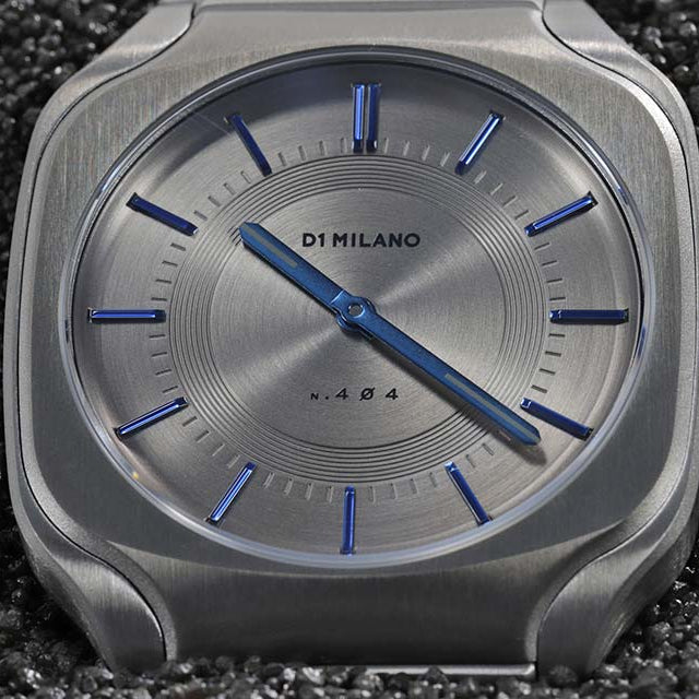 Close-up of D1 Milano SQBJ02 dial showing sunburst pattern and blue hour markers