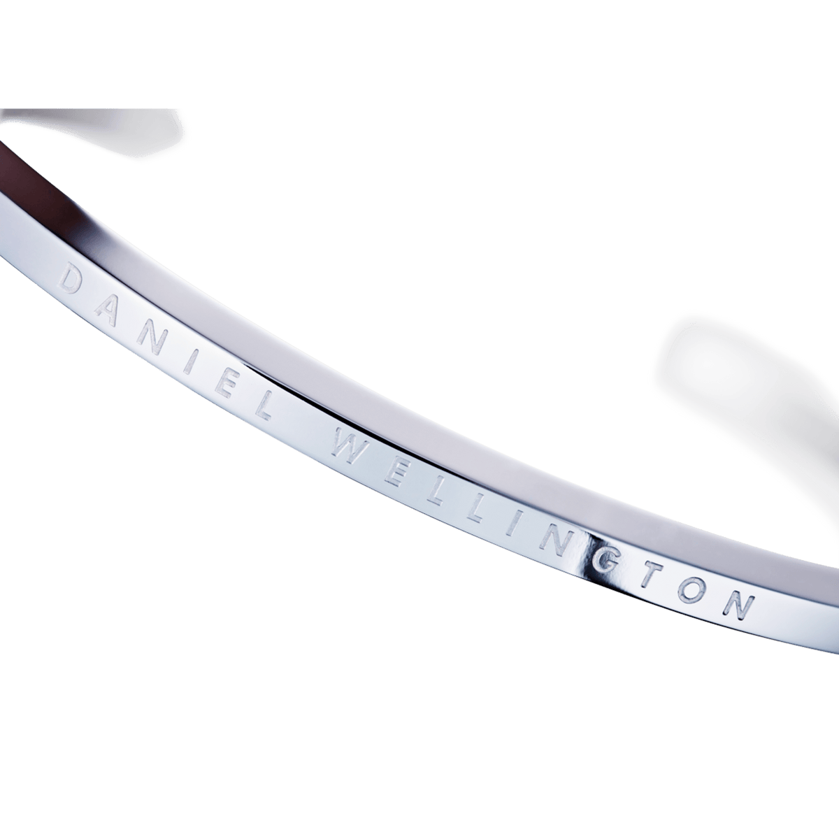 Close-up of silver cuff bracelet showing engraved branding on inner surface