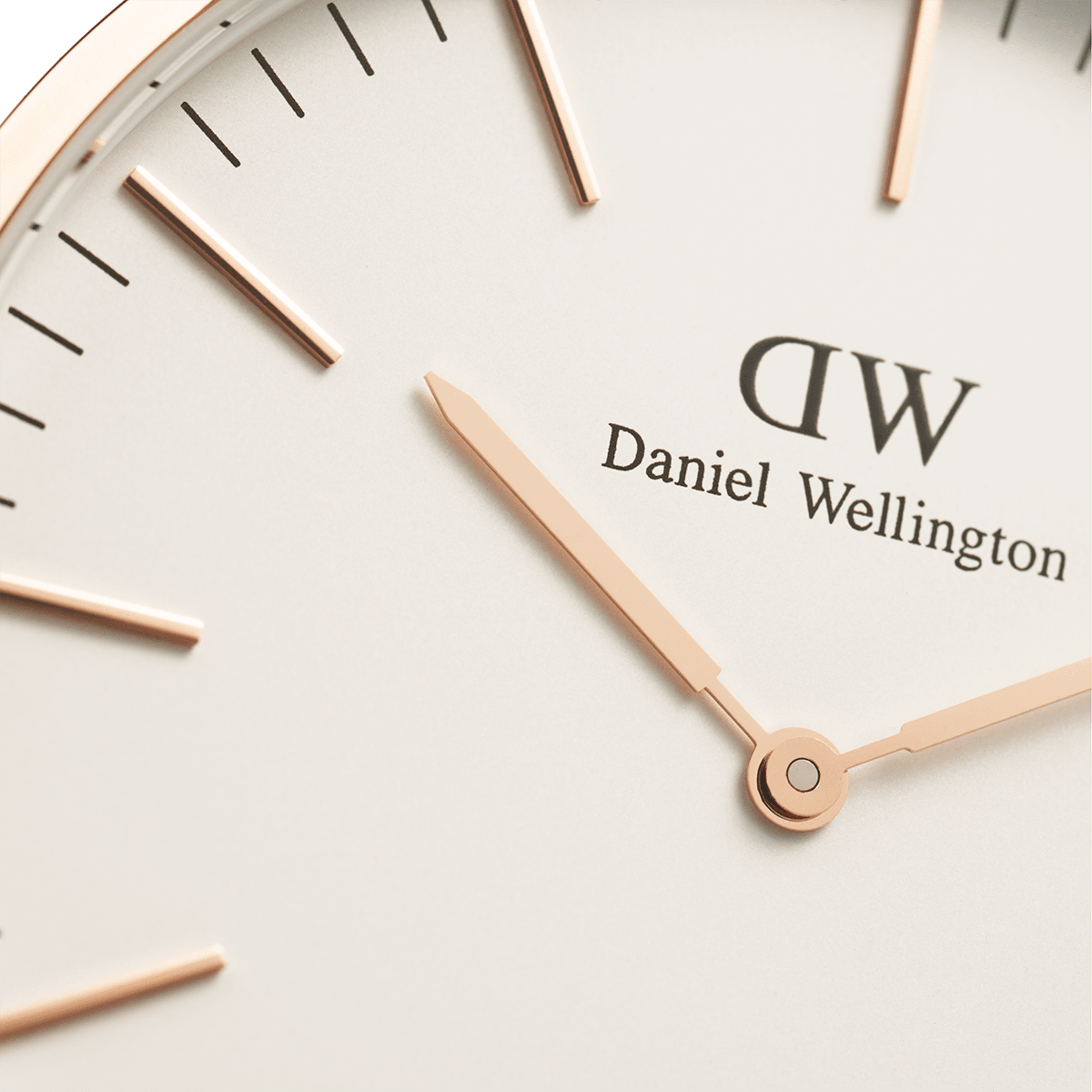 Close-up of white dial with rose gold hands, hour markers, and Daniel Wellington branding