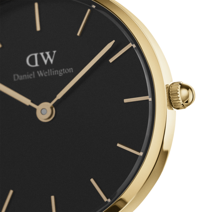 Close-up of black dial with gold hour markers, hands, and Daniel Wellington branding