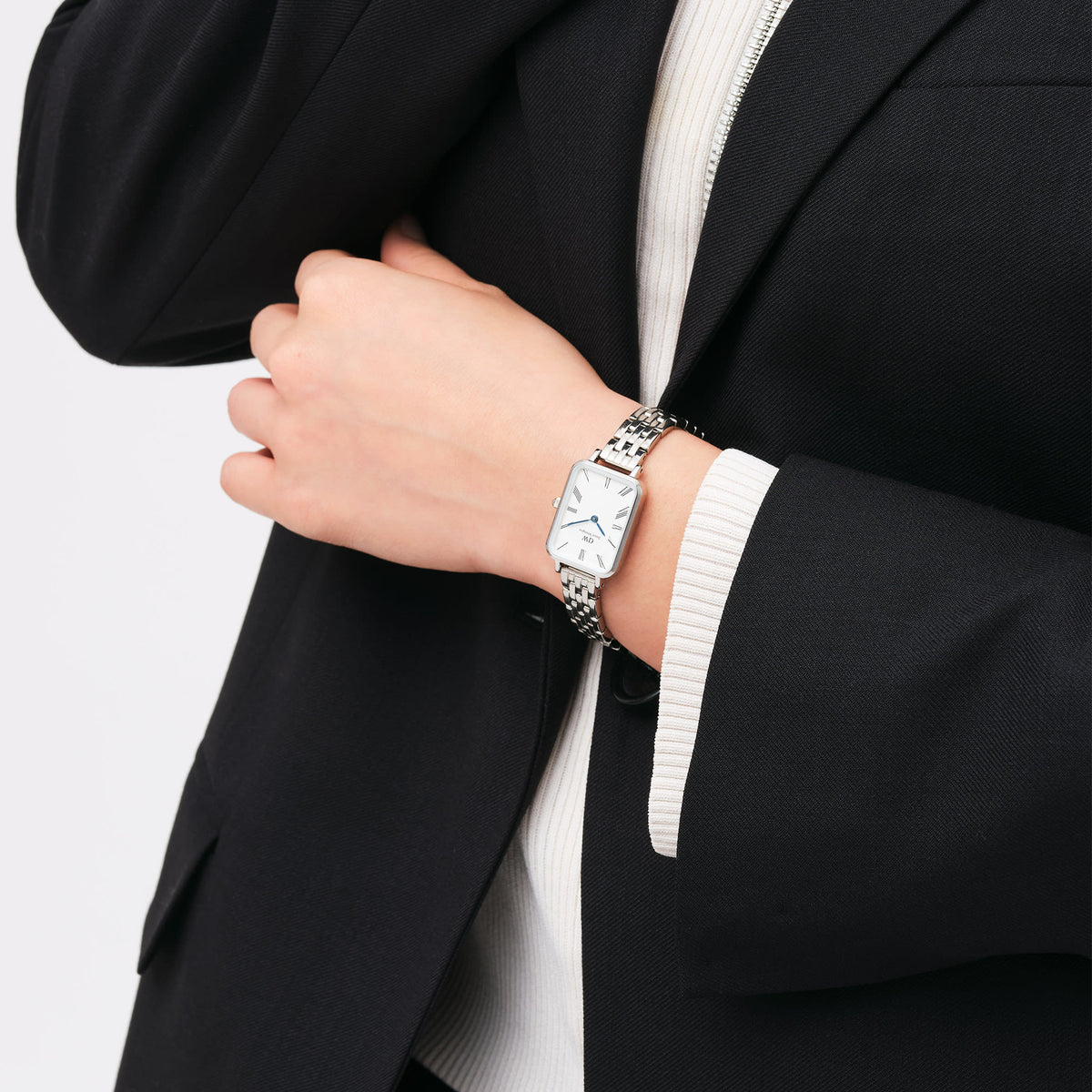 Daniel Wellington Quadro women's watch worn on wrist with silver bracelet and white rectangle dial