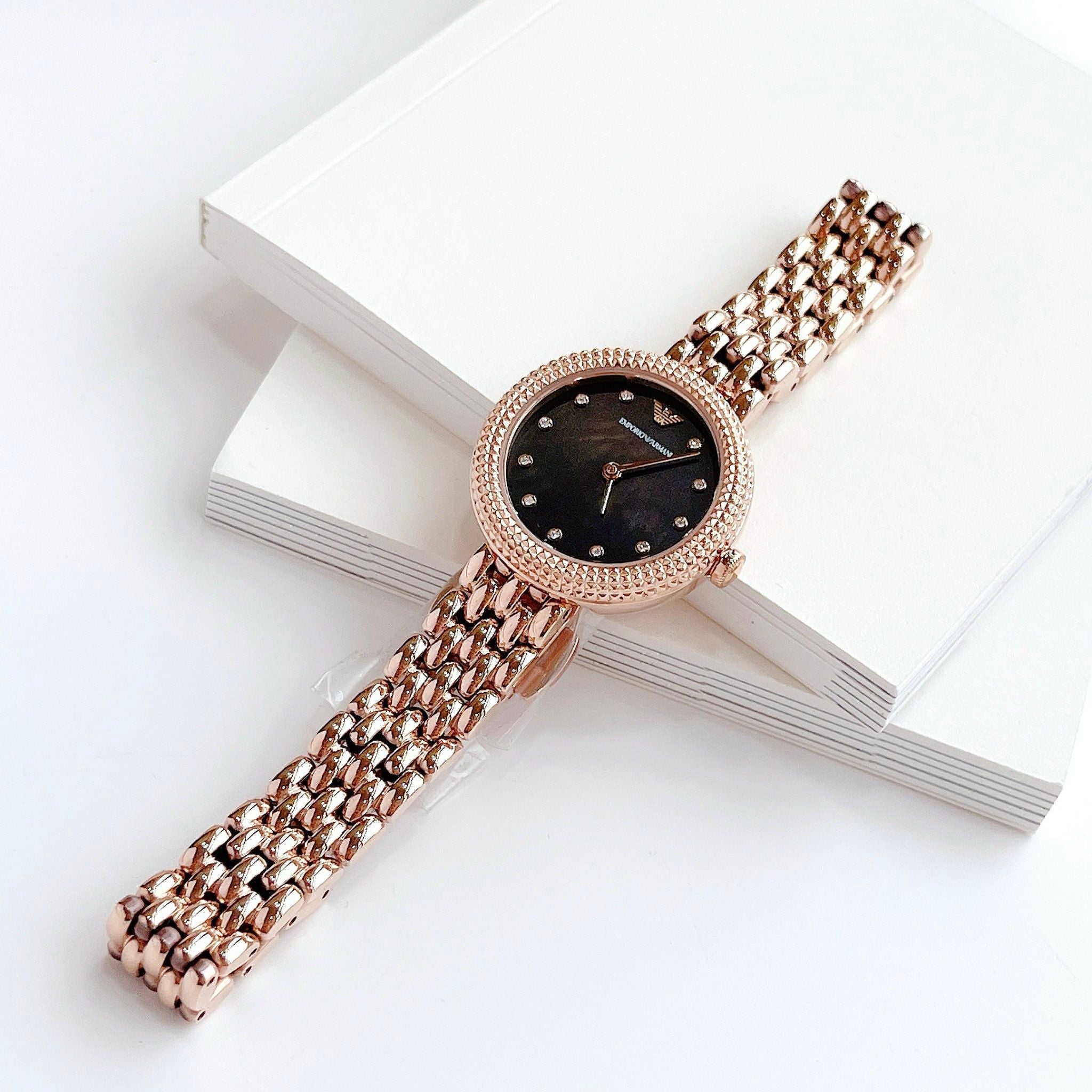 Emporio Armani AR11372 women's watch styled on wrist with white box, showing rose gold case and black dial