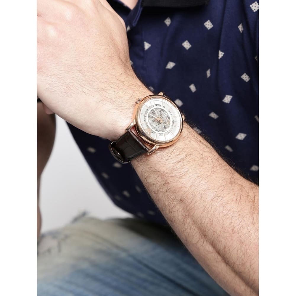 Emporio Armani AR1983 skeleton watch worn on male wrist with navy patterned shirt