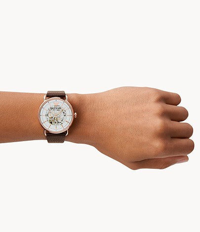 Skeleton dial watch on wrist showing white dial with rose gold case