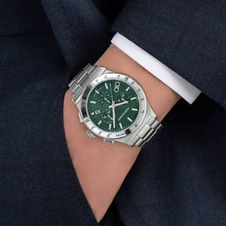 Watch worn on wrist, green dial visible with silver steel bracelet