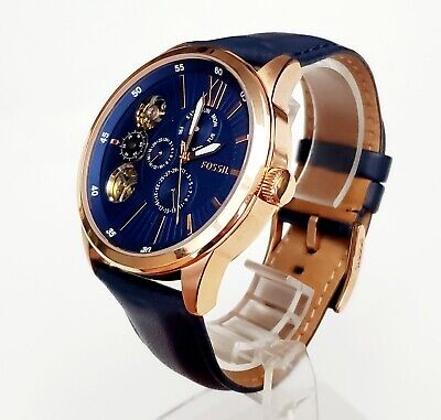 Fossil Flynn mechanical watch worn on wrist, showing rose gold case and navy leather strap