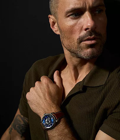 Fossil Inscription automatic watch worn on wrist showing blue dial and brown leather strap