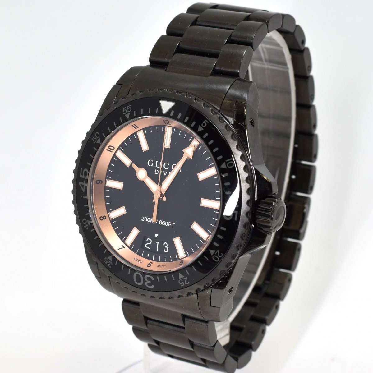 Gucci Dive watch angled view showing black steel bracelet and rose gold bezel accent