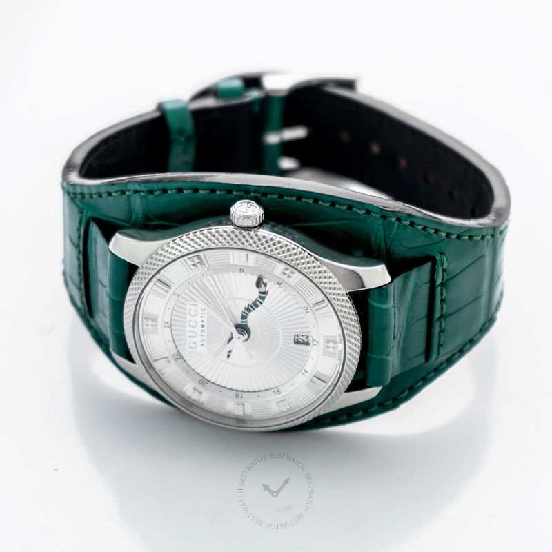 Gucci G-Timeless automatic watch worn on wrist, showing silver dial and green leather band