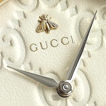 Close-up of white dial showing GG pattern, Gucci branding, and gold bee motif