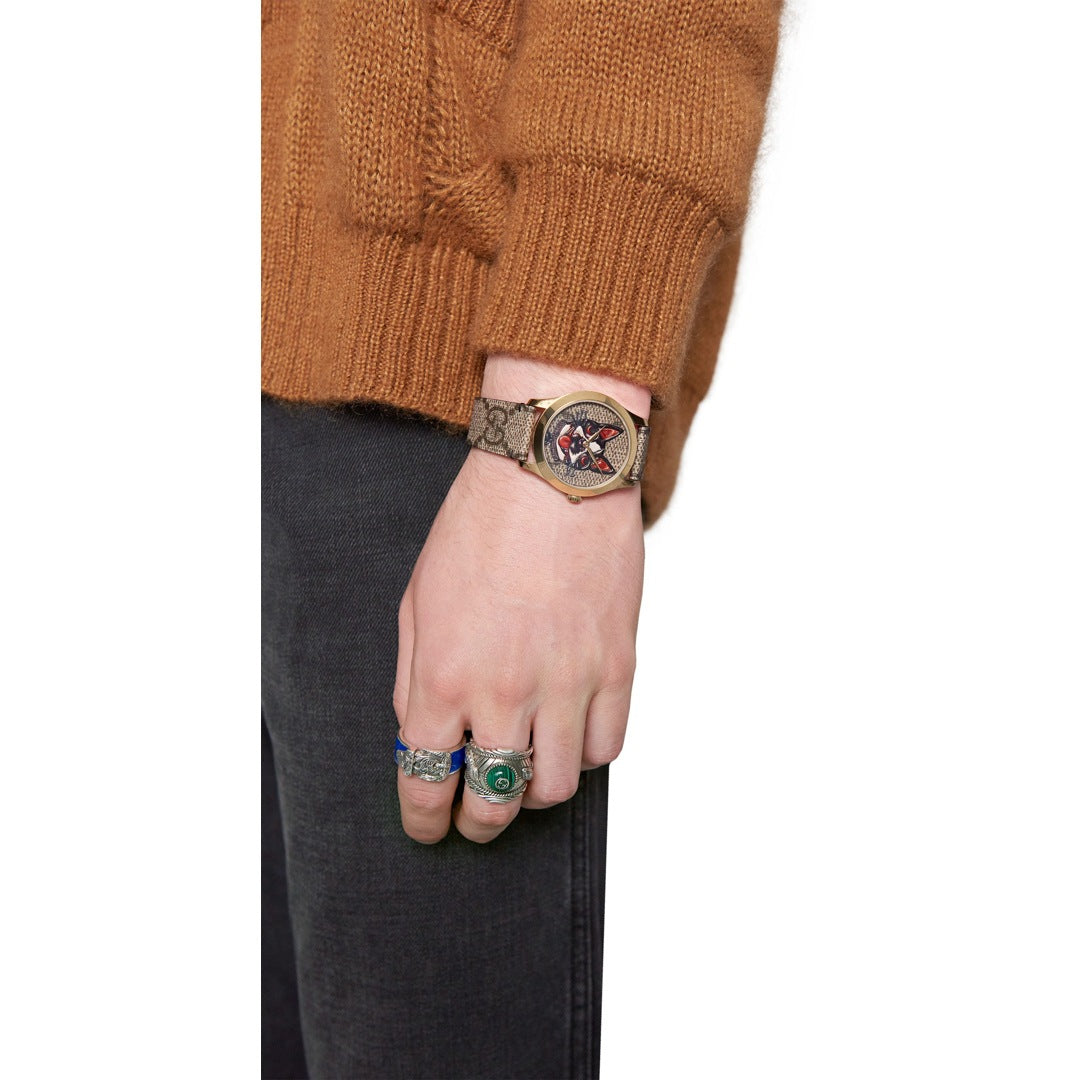 Gucci G-Timeless watch worn on wrist with brown dial and patterned strap