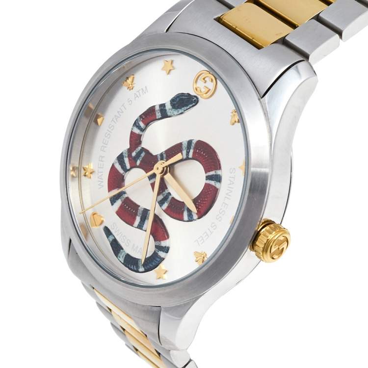 Angled view of Gucci G-Timeless watch showing silver and gold two-tone bracelet with snake dial