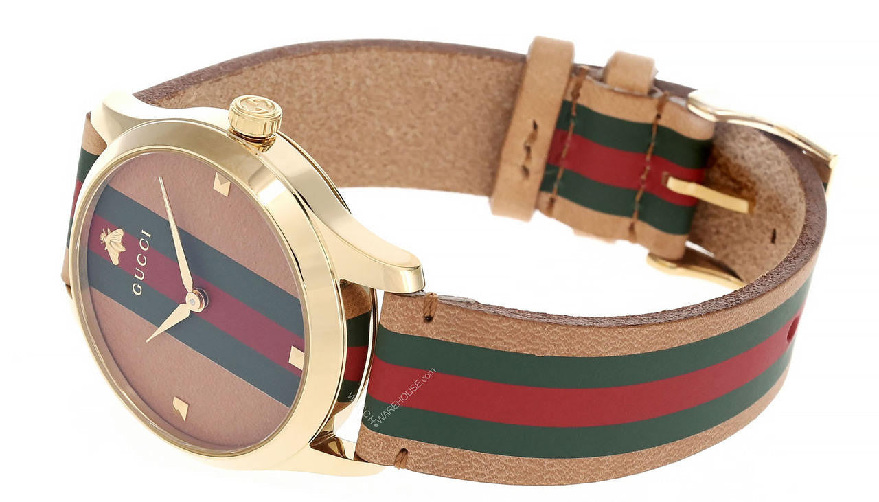 Gucci G-Timeless watch worn on wrist displaying tan dial and iconic striped strap