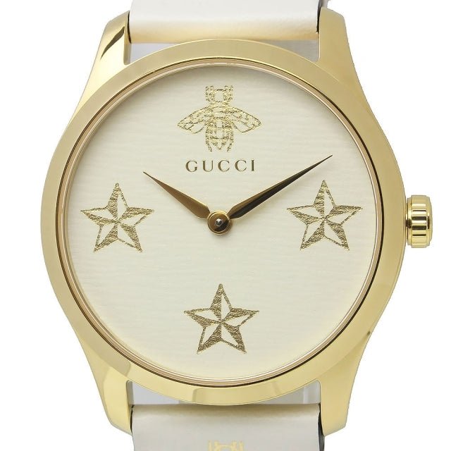 Close-up detail of Gucci G-Timeless watch dial showing gold stars, bee logo, and text