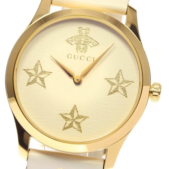 Detailed view of Gucci G-Timeless watch face with star pattern and bee emblem in gold