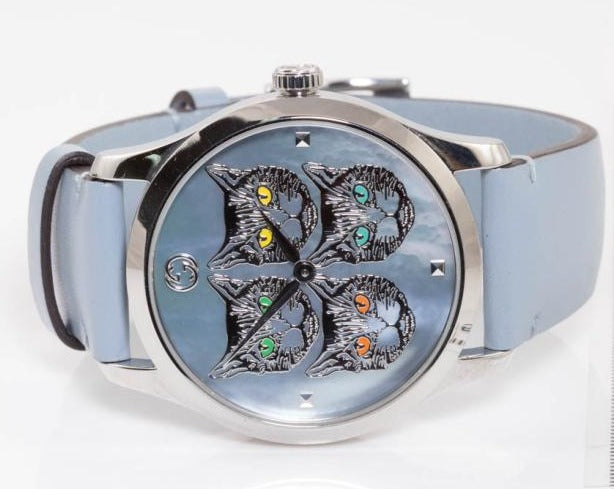 Angled view of G-Timeless 38mm watch showing embroidered cat faces and silver case