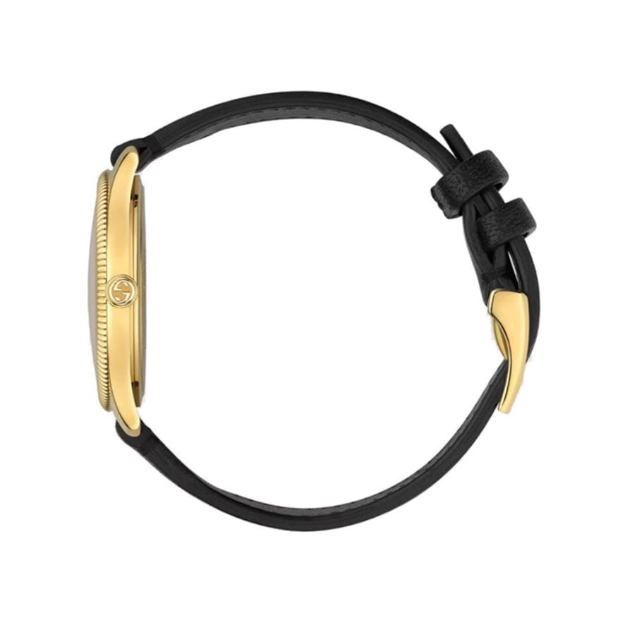 Gucci G-Timeless watch on wrist showing yellow gold case with black leather strap