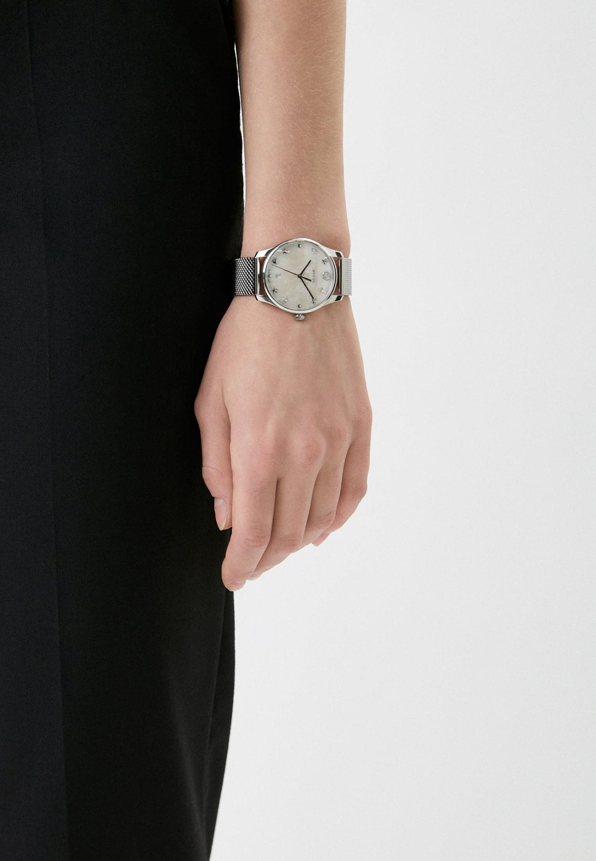 Gucci G-Timeless mother of pearl watch worn on wrist with stainless steel mesh band