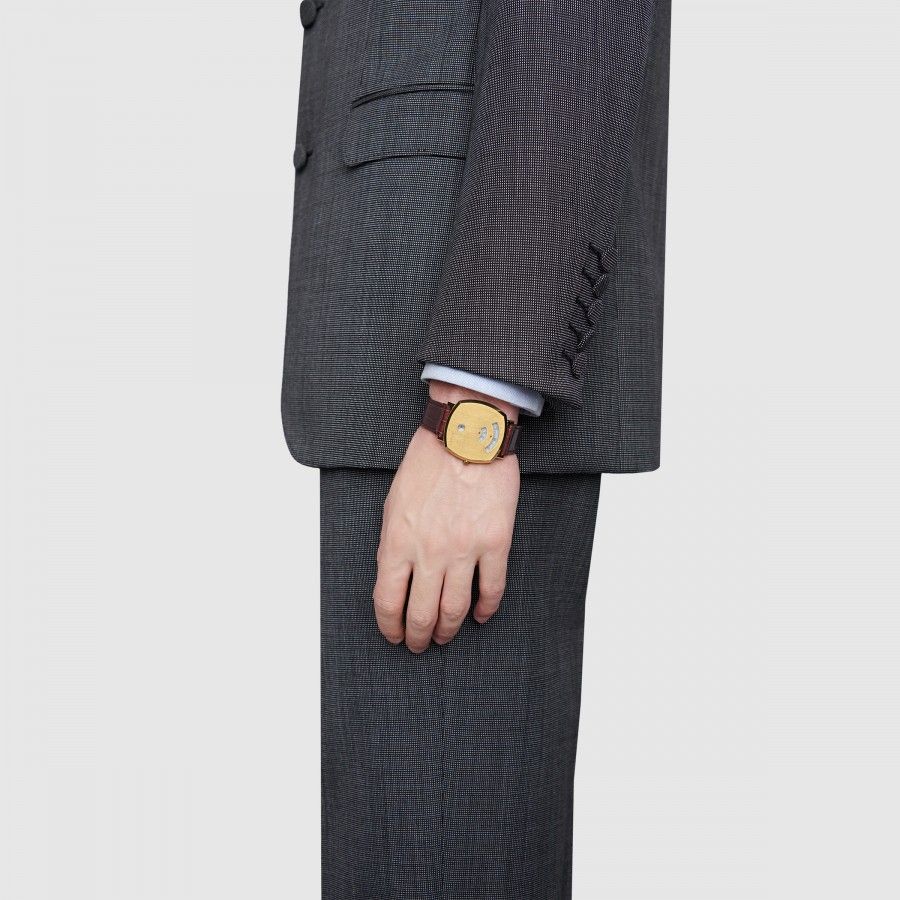 Gucci Grip watch with burgundy strap worn on wrist with charcoal suit