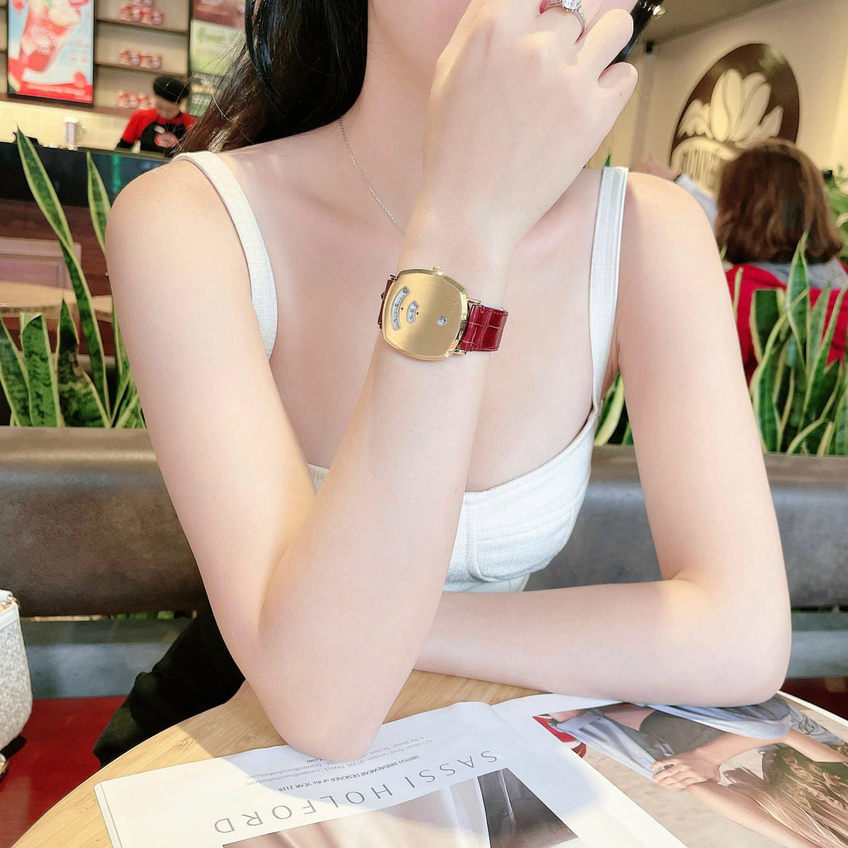 Gucci Grip watch with gold case and burgundy strap worn on wrist in lifestyle setting
