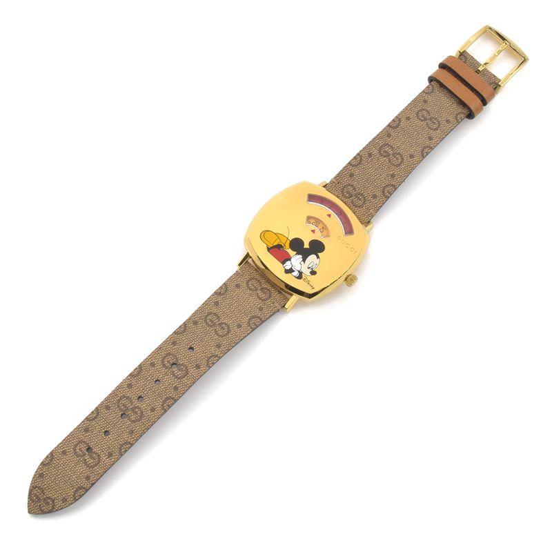 Gucci Grip watch on wrist showing gold square case with Mickey and Minnie design on brown monogram fabric strap