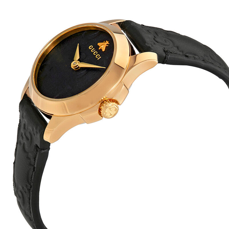 Gucci G-Timeless watch angled view showing gold-tone case, black dial, and black leather strap