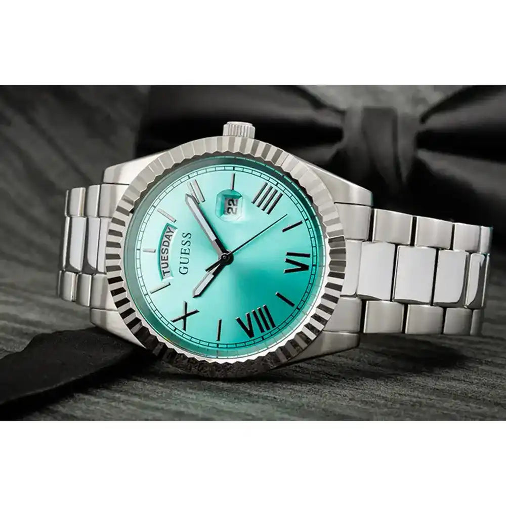 Angled view of Guess Connoisseur watch with turquoise dial, Roman numerals, and silver steel case