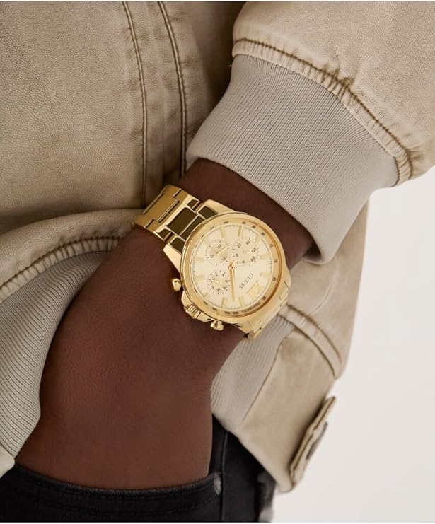 GUESS gold tone men's watch worn on wrist with beige and brown clothing