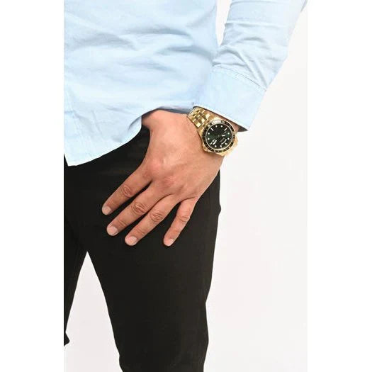 GUESS GW0220G2 gold watch worn on wrist with green dial and black bezel