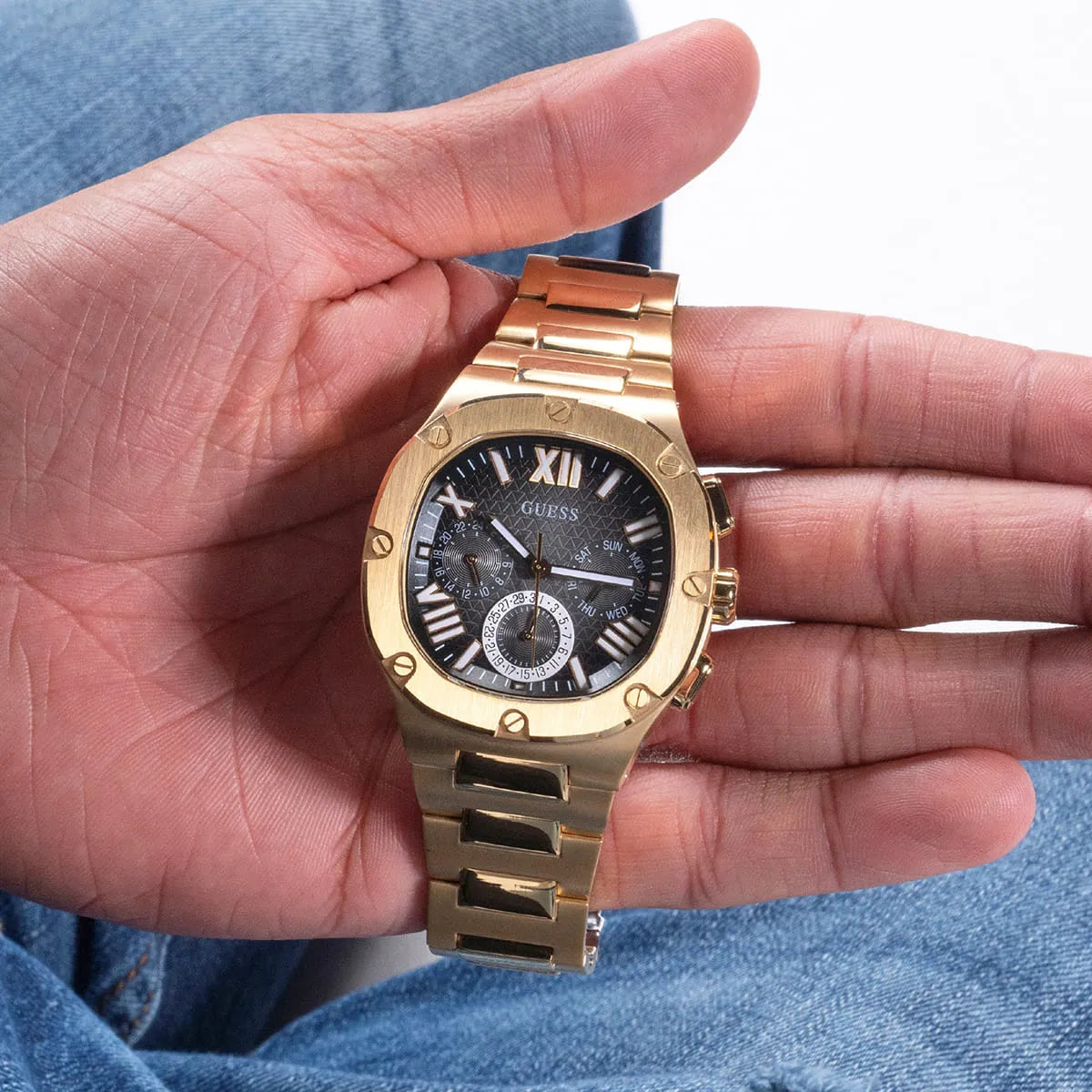 Guess GW0572G2 multifunction watch worn on wrist with gold-tone bracelet and black dial