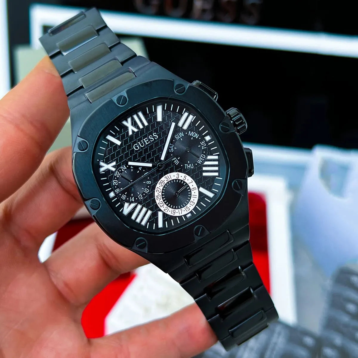 GUESS GW0572G3 held in hand showing black chronograph watch with multi-function dial
