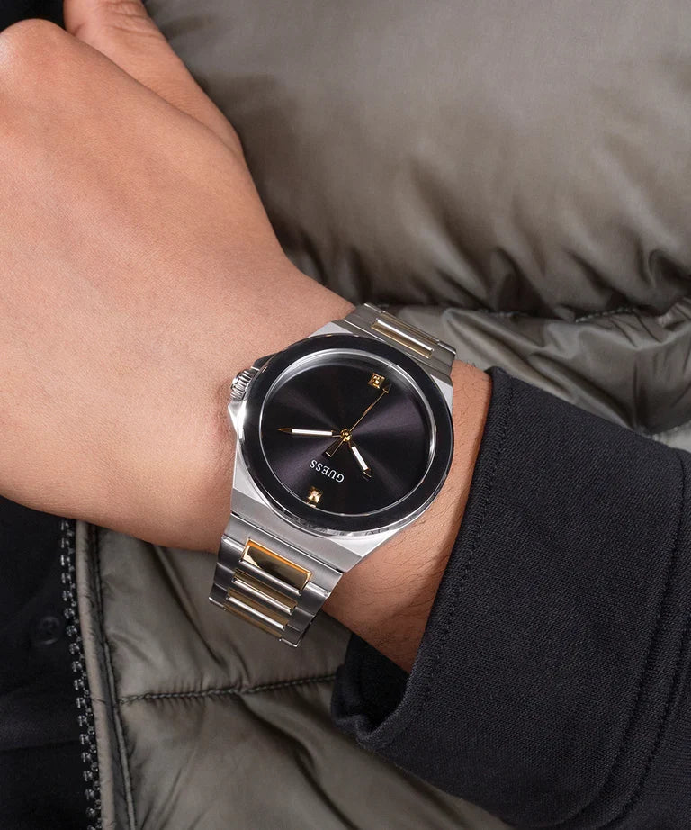 GUESS analog watch on wrist showing black dial and gold-tone hands, side-on view