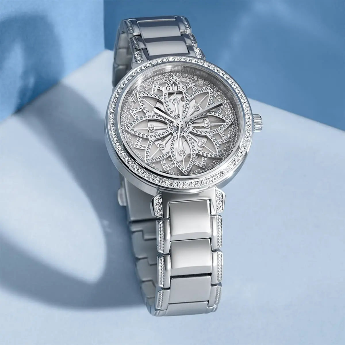 Guess Lily women's quartz watch displayed on blue background with silver dial and steel strap