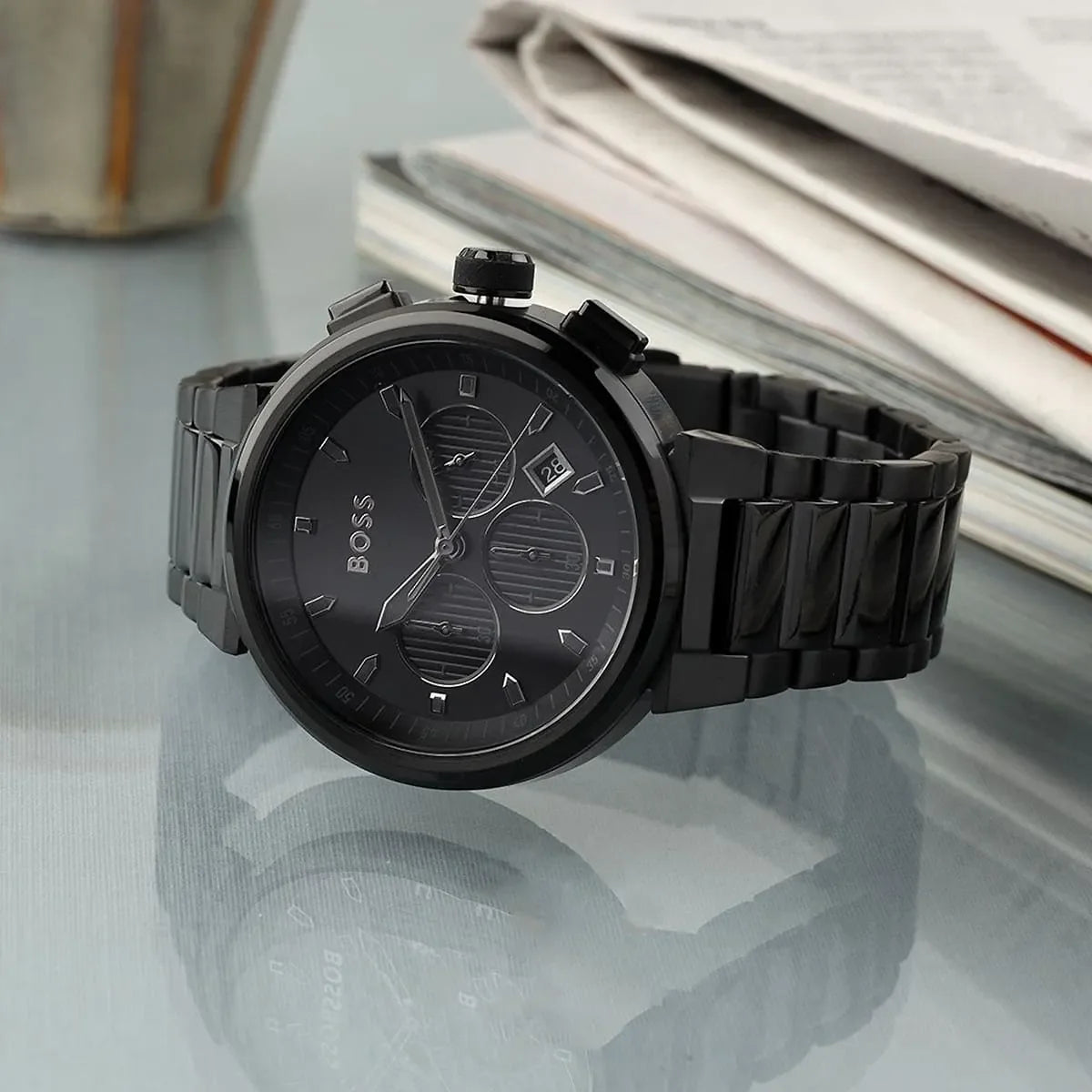 Hugo Boss 1514001 chronograph watch worn on wrist with magazines in background