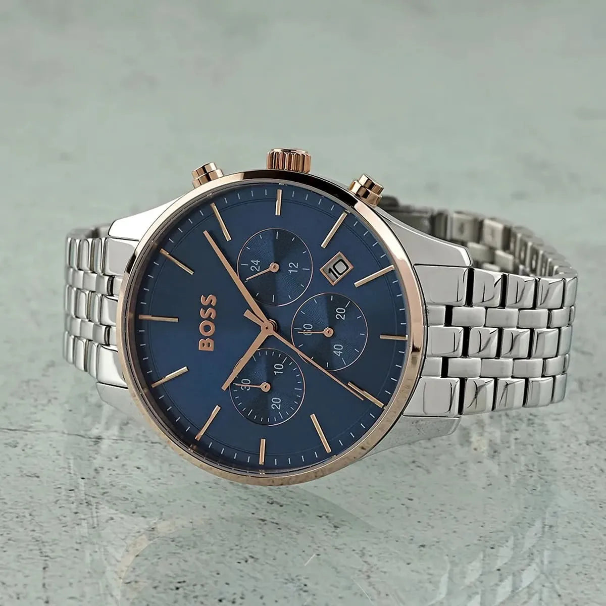 Hugo Boss Avery chronograph watch on gray surface showing blue dial with chronograph subdials and rose gold accents