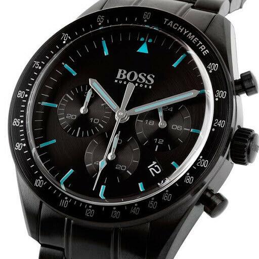 Close-up of black dial with blue hour markers, white hands, tachymetre bezel, and three subdials