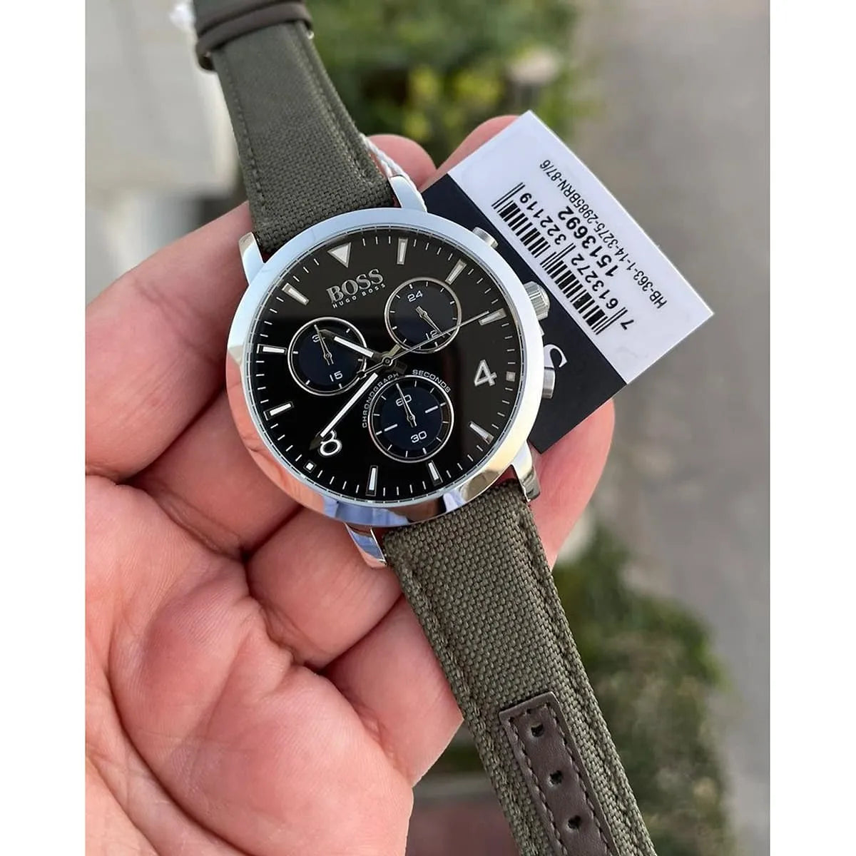Hugo Boss Vesada chronograph watch held in hand showing dial detail and green textile strap with tag