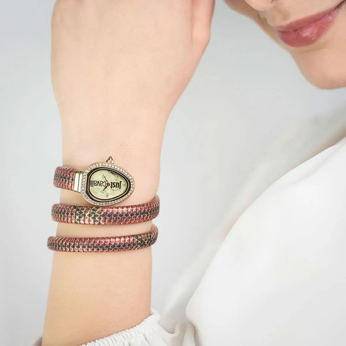 Just Cavalli gold watch worn on wrist with triple-wrap multicolored snake-textured bands stacked