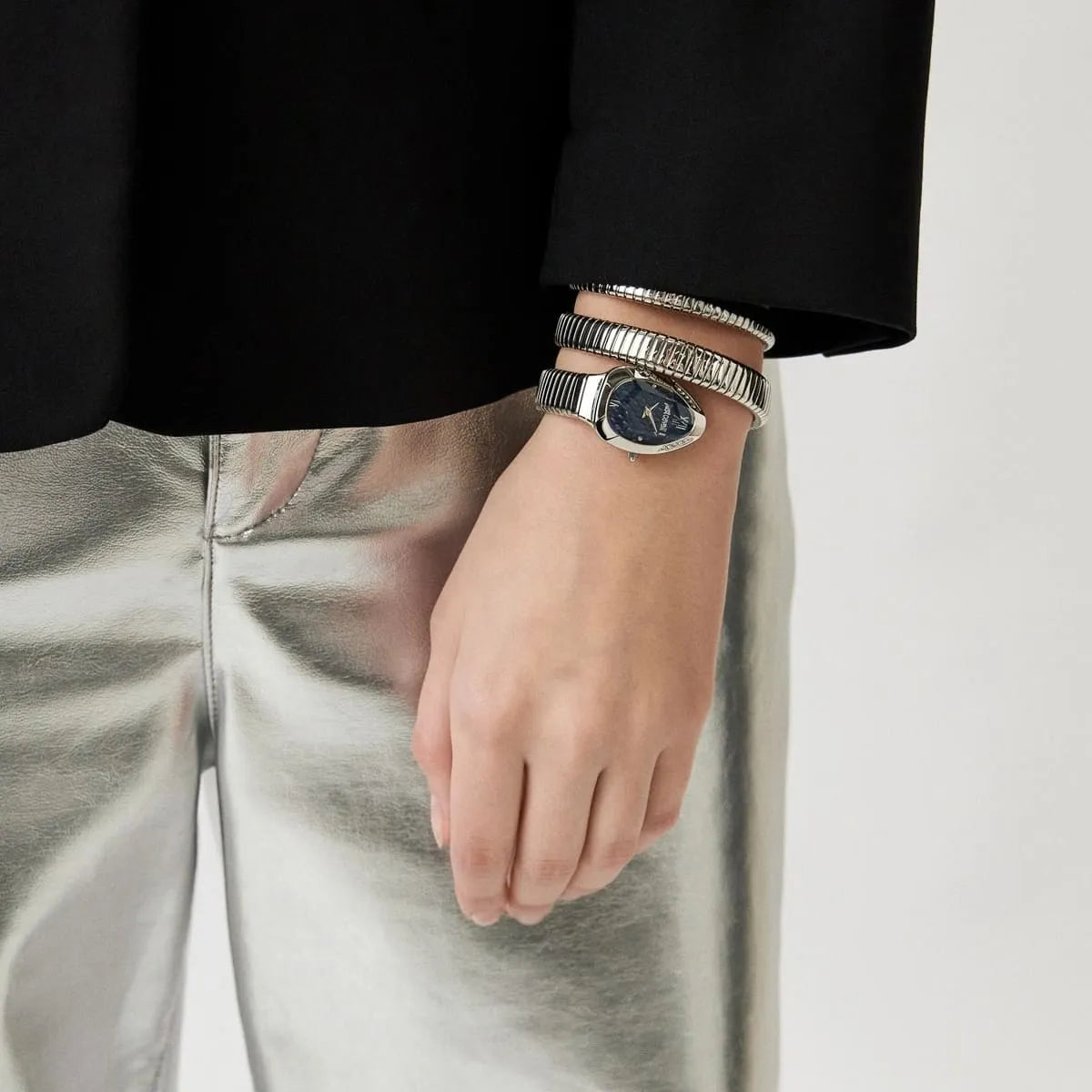 Woman wearing Just Cavalli Serpente Metallica watch with triple-wrap silver snake strap on wrist