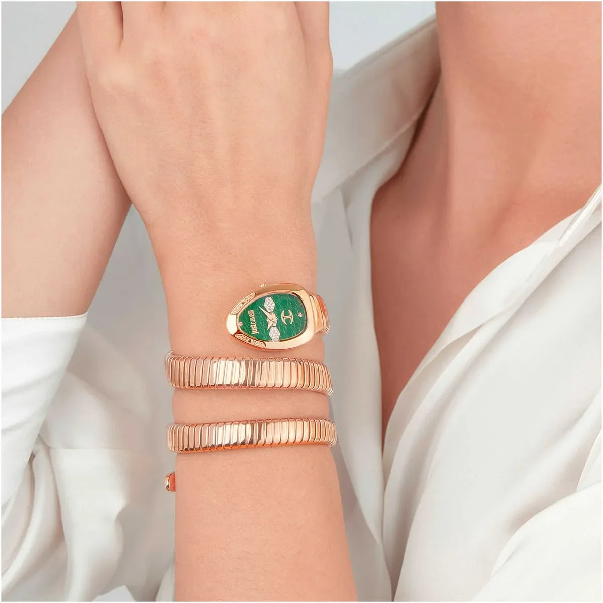 Watch worn on wrist with green dial and rose gold triple-wrap strap