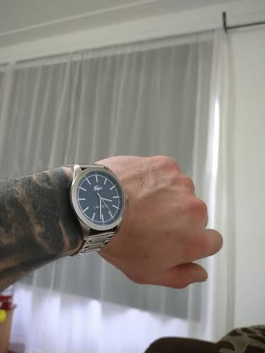 Lacoste men's watch with blue dial on wrist, stainless steel bracelet visible