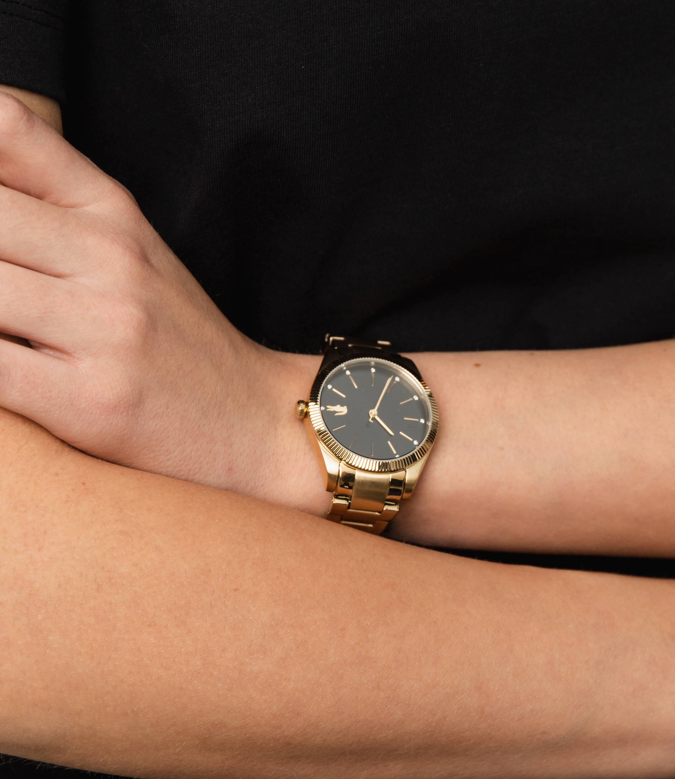Lacoste women's watch worn on wrist showing black dial and gold-tone case