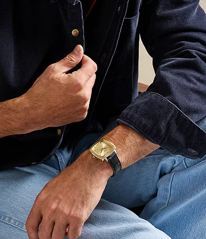 Nick Jonas Fossil Machine Luxe watch worn on wrist with gold case and black leather band